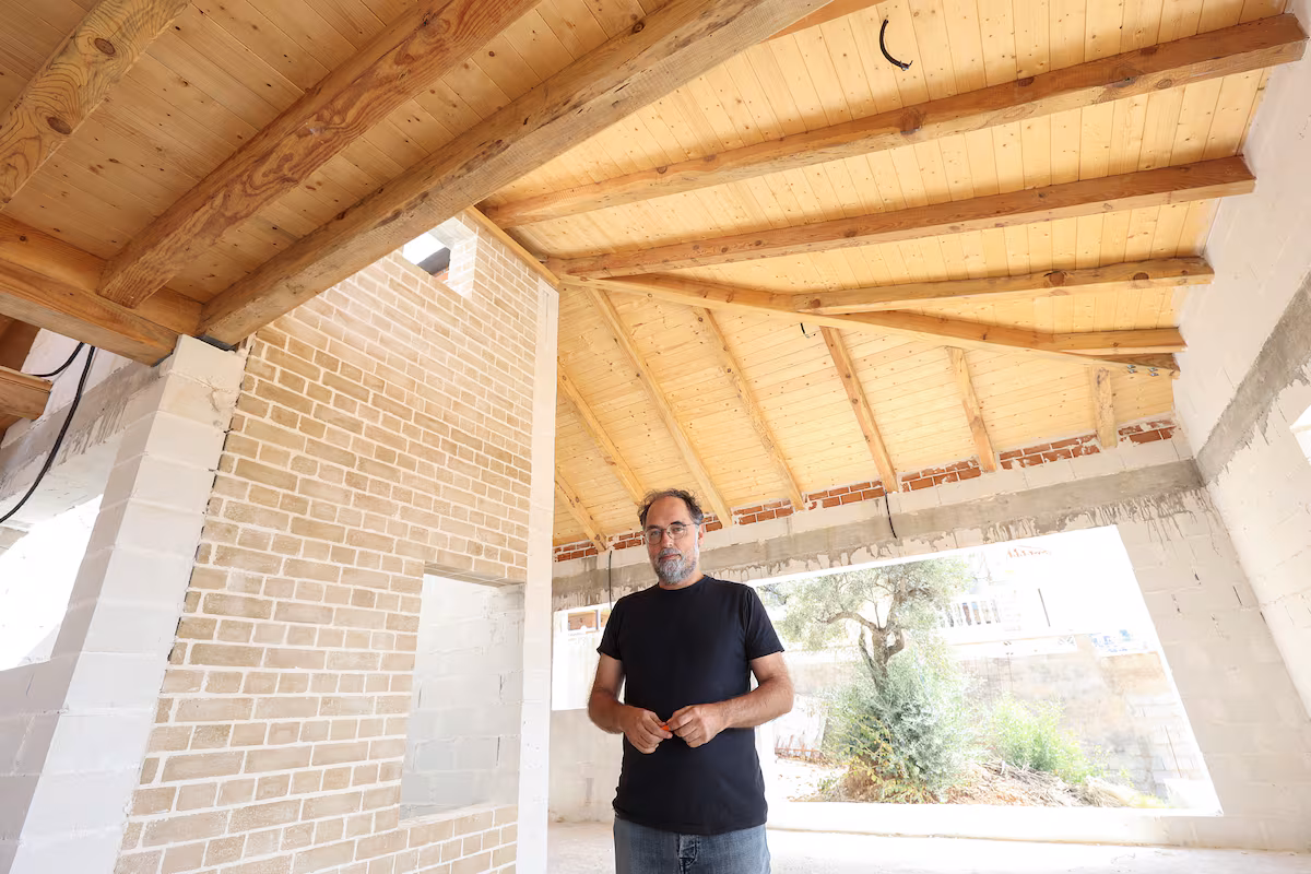 Pablo Farfán under a wooden structure salvaged from the Sierra Bermeja fire